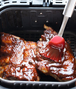 air fryer ribs in air fryer basket with bbq sauce